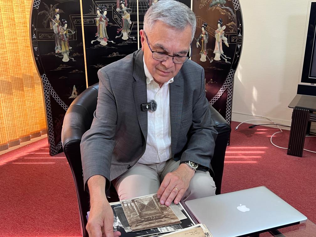 2025年6月23日,贝石涛在巴黎近郊接受记者采访时翻看与贝熙业医生相关的历史资料。新华社记者 孙鑫晶 摄